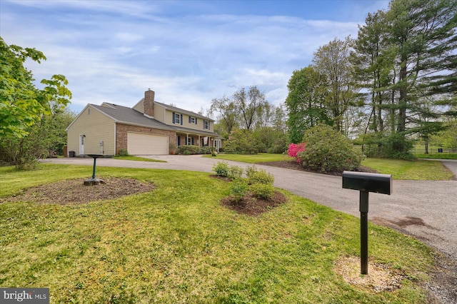 view of front of home with brick siding, an attached garage, a front lawn, and aphalt driveway