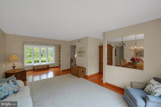 living room with a chandelier, baseboards, visible vents, and wood finished floors