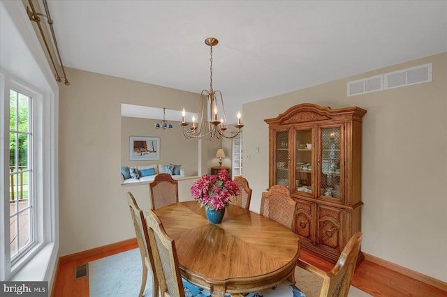 dining space with light wood-style floors, baseboards, visible vents, and a notable chandelier