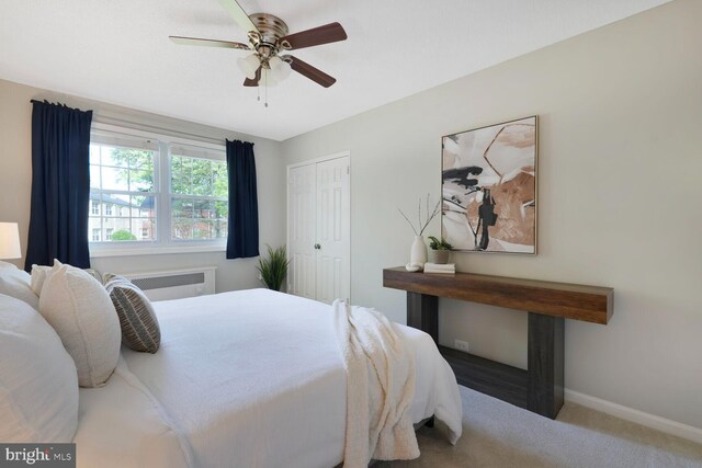 carpeted bedroom featuring radiator heating unit, baseboards, ceiling fan, and a closet