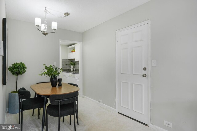 dining space featuring baseboards, a chandelier, and light carpet