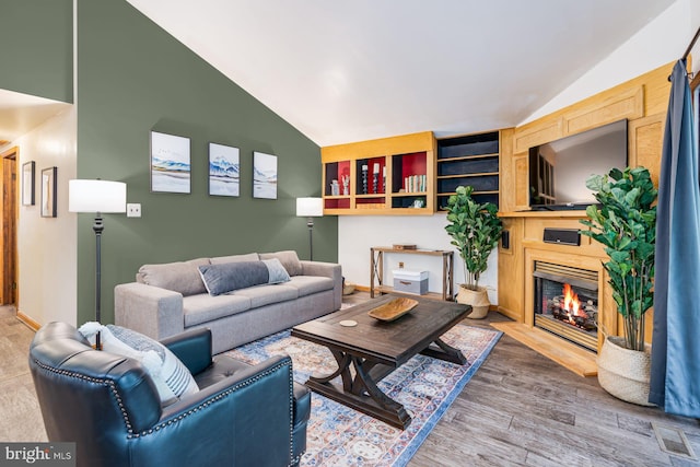 371 Oak Hill Rd, Berkeley Springs, WV 25411 - living room with baseboards, vaulted ceiling, a fireplace with flush hearth, and wood finished floors