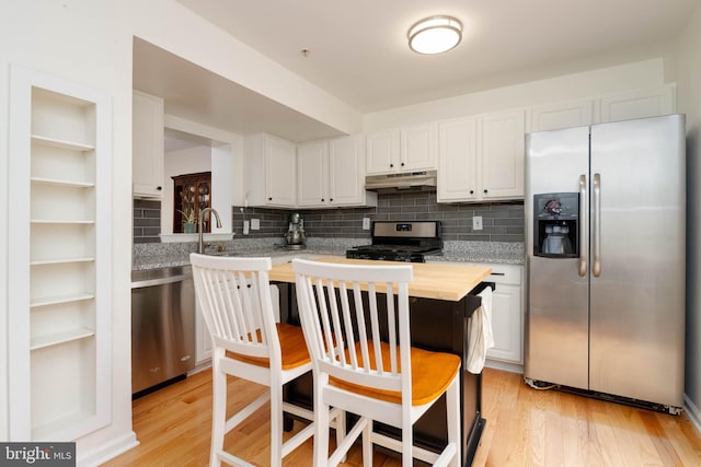 6126 Quiet Times, Columbia, MD 21045 - kitchen with appliances with stainless steel finishes, under cabinet range hood, light wood finished floors, white cabinets, and tasteful backsplash