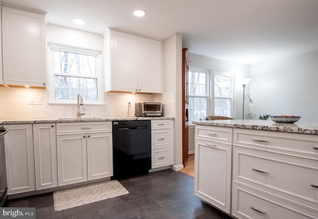 kitchen featuring plenty of natural light, a sink, white cabinetry, and black dishwasher