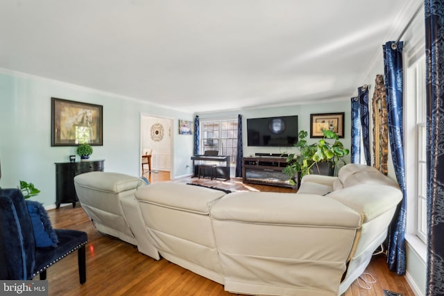 living area with ornamental molding and wood finished floors