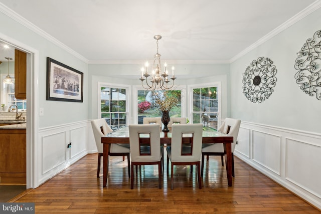 dining space with an inviting chandelier, ornamental molding, hardwood / wood-style flooring, and a decorative wall