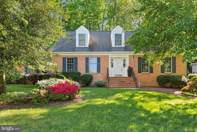 cape cod house with brick siding, a shingled roof, and a front yard