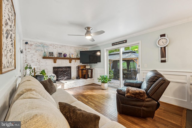 living area featuring crown molding, ceiling fan, a fireplace, and hardwood / wood-style floors
