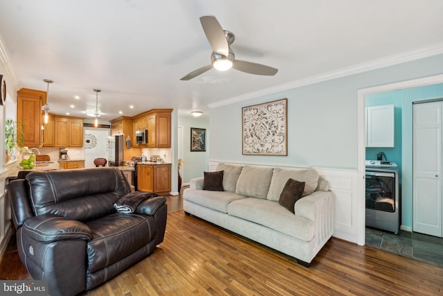 living room with crown molding, a ceiling fan, washer / dryer, and dark wood-type flooring