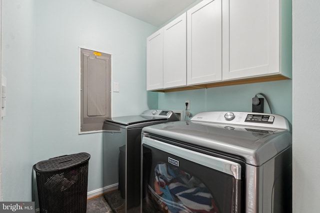 clothes washing area with baseboards, electric panel, cabinet space, and washer and dryer