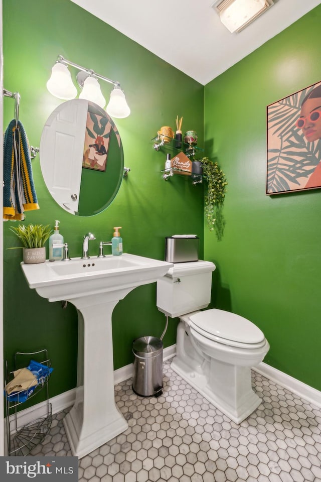 bathroom with baseboards, tile patterned floors, and toilet