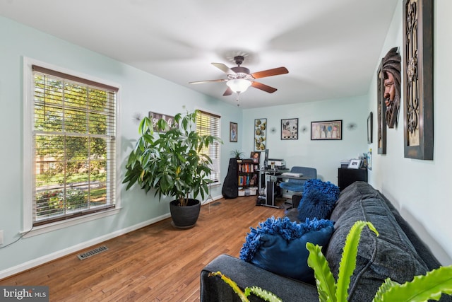 interior space featuring a ceiling fan, baseboards, visible vents, and wood finished floors