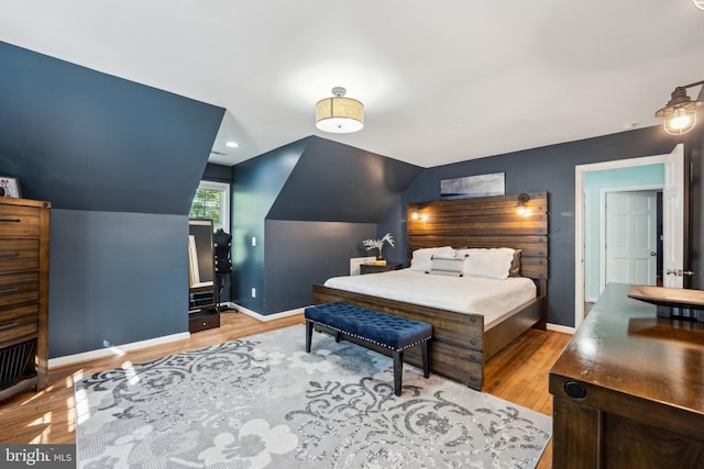 bedroom featuring baseboards, wood finished floors, and vaulted ceiling