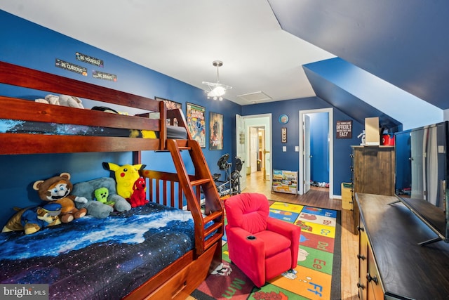bedroom with vaulted ceiling and wood finished floors