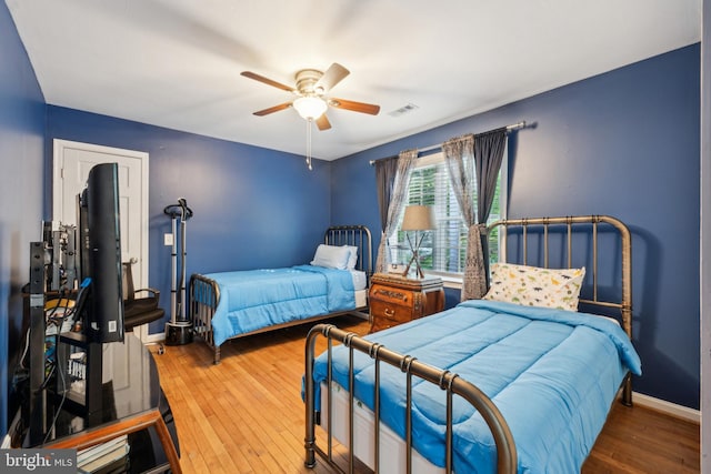 bedroom featuring baseboards, ceiling fan, hardwood / wood-style floors, and visible vents