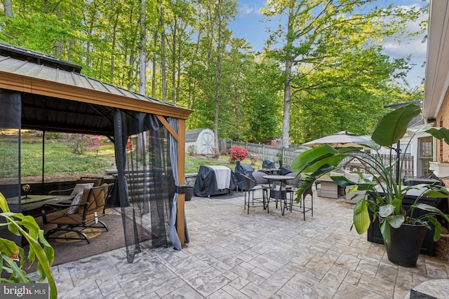 view of patio / terrace featuring grilling area, outdoor dining area, a fenced backyard, a shed, and a gazebo