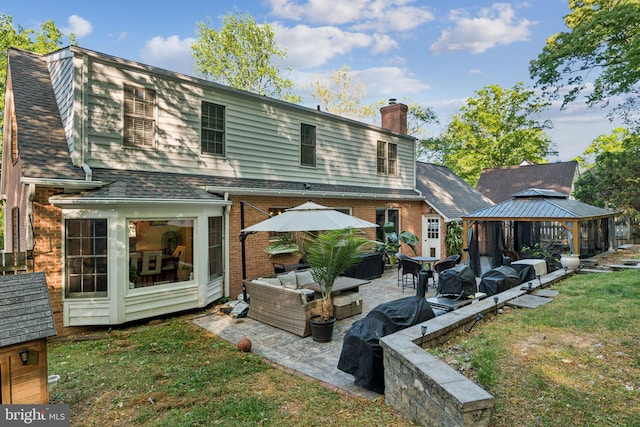 rear view of house featuring outdoor lounge area, a patio, a chimney, brick siding, and a gazebo