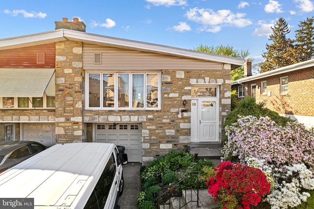 view of front facade featuring a chimney, a garage, and stone siding