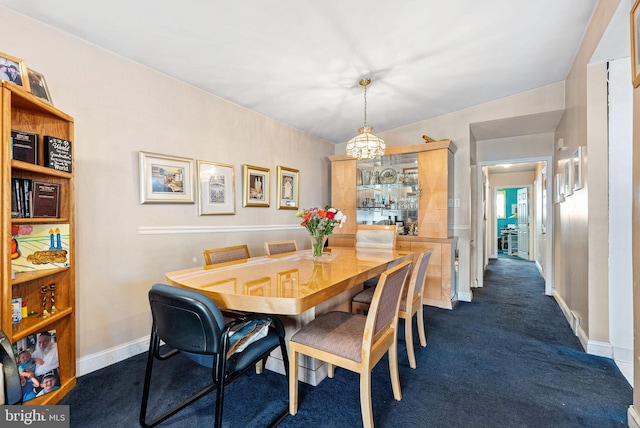 dining room featuring baseboards, a chandelier, and dark carpet