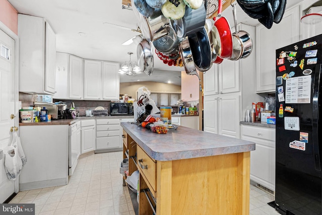 kitchen with dark countertops, a kitchen island, black appliances, and white cabinets