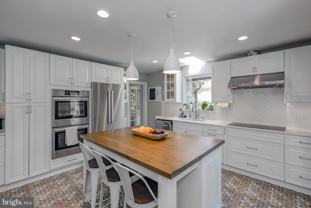 kitchen featuring wooden counters, a sink, under cabinet range hood, stainless steel appliances, and recessed lighting