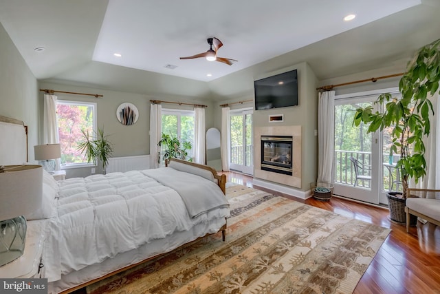 bedroom with visible vents, lofted ceiling, wood finished floors, a fireplace, and access to exterior