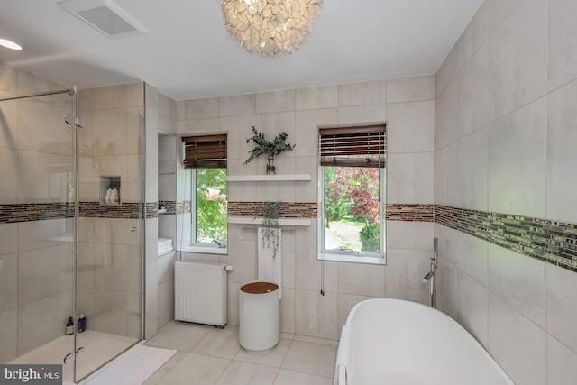 bathroom with visible vents, tile walls, tile patterned flooring, a stall shower, and radiator heating unit