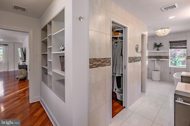 hallway with tile walls, built in features, and visible vents