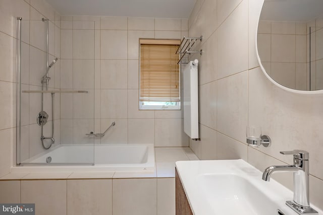 full bath with a sink, tile walls, and tiled shower / bath