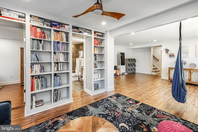 interior space with ceiling fan, built in features, stairs, baseboards, and wood finished floors