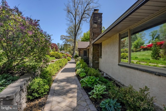 view of home's exterior featuring stucco siding, stone siding, and a chimney