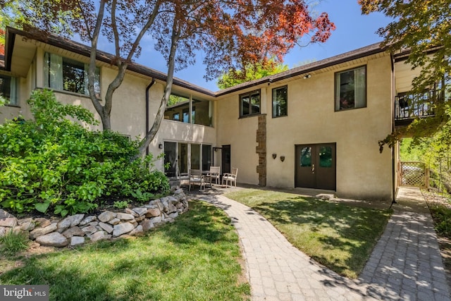 rear view of house with a patio, french doors, stucco siding, and a yard