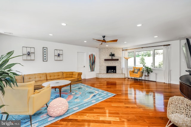 living area with ceiling fan, a large fireplace, recessed lighting, wood finished floors, and visible vents