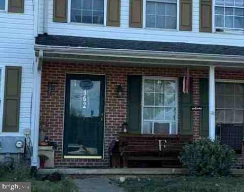view of exterior entry featuring a porch and brick siding