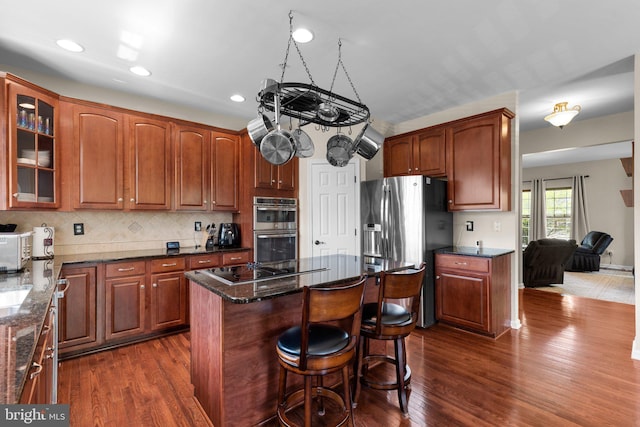 kitchen with dark wood-type flooring, glass insert cabinets, a center island, and stainless steel appliances