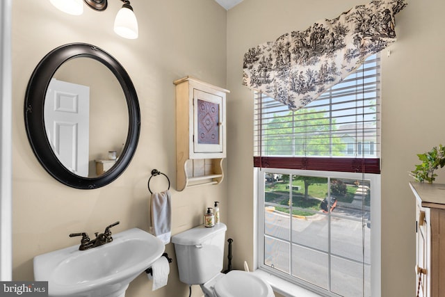 bathroom featuring a sink, a healthy amount of sunlight, and toilet