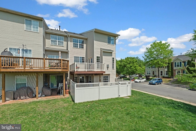 back of house with fence, a wooden deck, and a yard