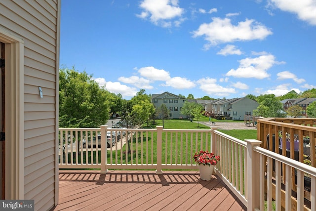wooden terrace featuring a lawn and a residential view