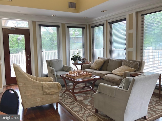 living area featuring visible vents, ornamental molding, and wood finished floors