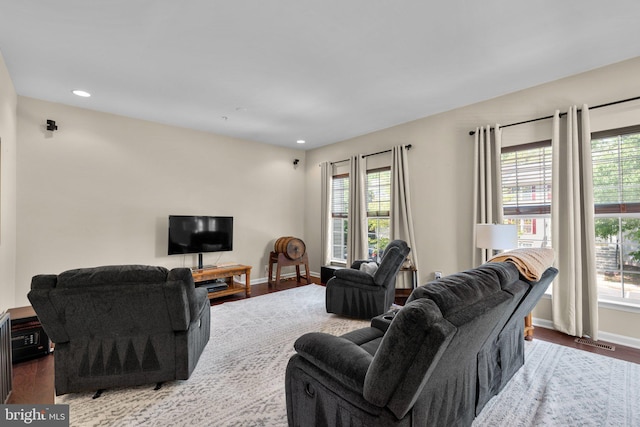 living area featuring visible vents, baseboards, wood finished floors, and a healthy amount of sunlight