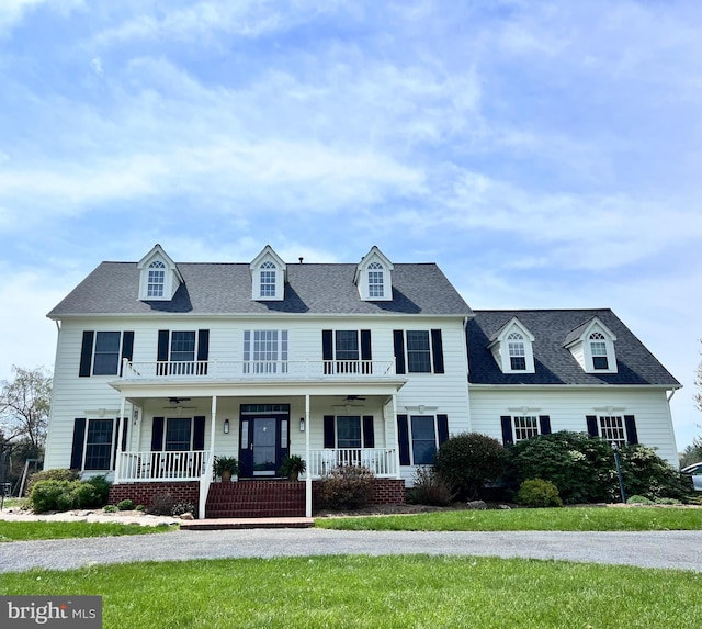 colonial-style house with ceiling fan, a porch, and a front lawn