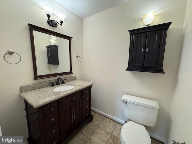 half bath with baseboards, vanity, and toilet