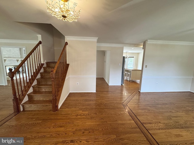 staircase featuring crown molding, baseboards, wood finished floors, and a chandelier