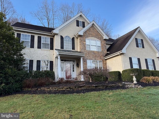 view of front facade with a front lawn, stone siding, and stucco siding