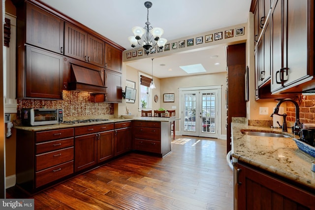 2636 N Calvert St N, Baltimore, MD 21218 - kitchen with a sink, stainless steel gas cooktop, a peninsula, decorative backsplash, and dark wood-style floors