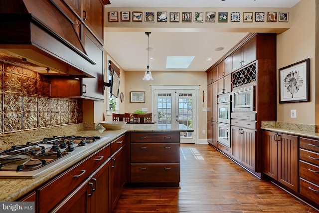 2636 N Calvert St N, Baltimore, MD 21218 - kitchen with appliances with stainless steel finishes, dark wood-type flooring, a peninsula, a skylight, and backsplash
