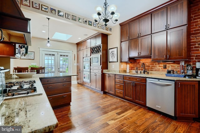 2636 N Calvert St N, Baltimore, MD 21218 - kitchen with stainless steel appliances, a sink, a skylight, and hardwood / wood-style floors