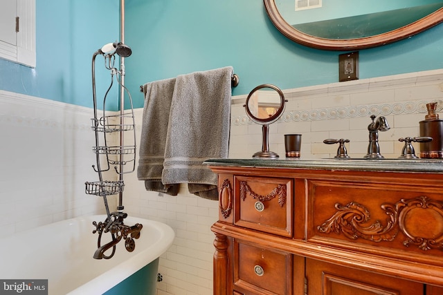 2636 N Calvert St N, Baltimore, MD 21218 - bathroom with a soaking tub, tile walls, wainscoting, and vanity