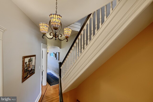 2636 N Calvert St N, Baltimore, MD 21218 - staircase with a chandelier, wood finished floors, and baseboards