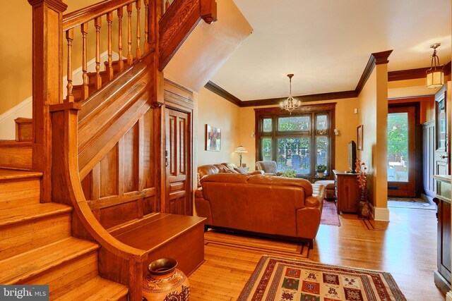 2636 N Calvert St N, Baltimore, MD 21218 - living area featuring a chandelier, stairs, light wood-style floors, and crown molding